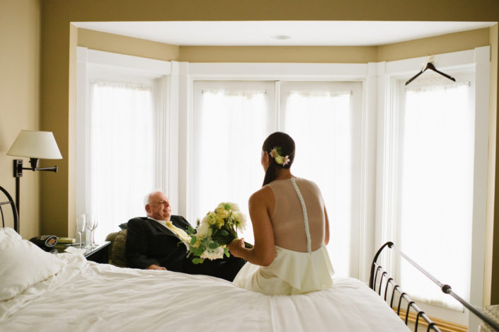 Bride talking with the father of the bride in a guest room at the Inn at Black Star Farms.