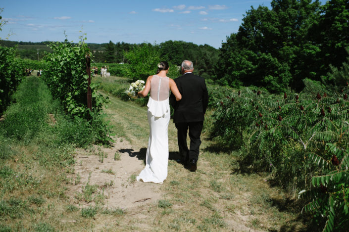 Father of the bride walking the bride through the vineyard at Black Star Farms Suttons Bay.