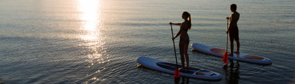 Couple using stand-up paddle boards as part of the Outdoor Adventure Package at the Inn at Black Star Farms.
