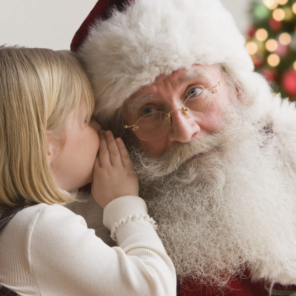 Girl whispering into Santa's ear.