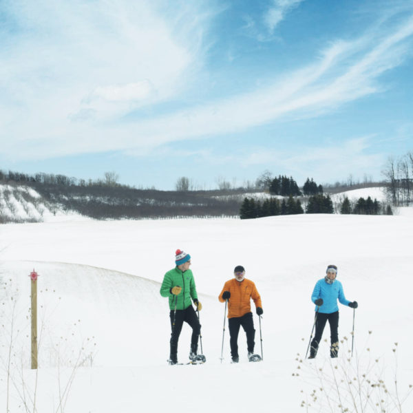 Three people snowshoeing on the trails at Black Star Farms Suttons Bay.