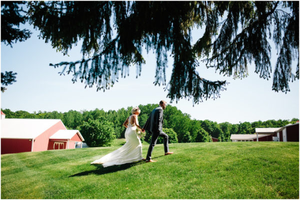 Bride and groom walking on the lawn with a barn in the background.