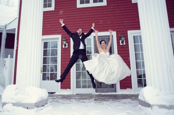 Bride and groom jumping during winter on the front porch of Inn at Black Star Farms.