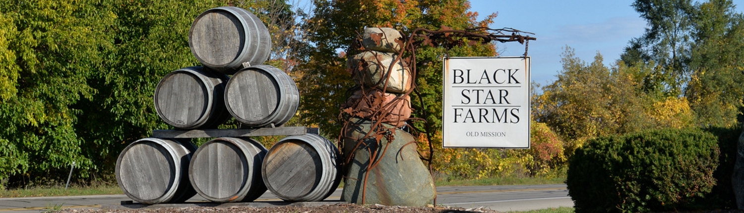 Black Star Farms Old Mission sign with wine barrels.
