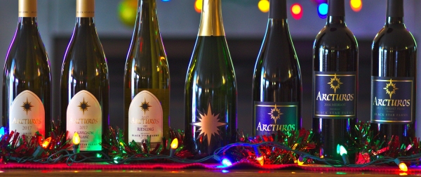 Bottles of sparkling, white, and red wine with festive lights.