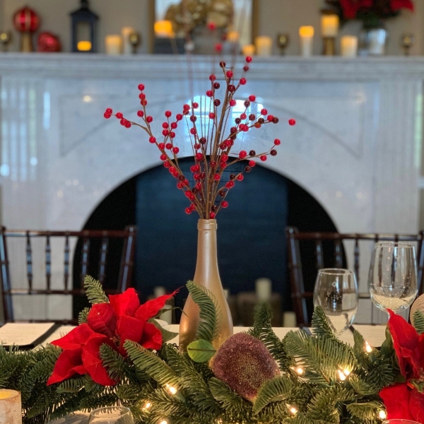 Holiday table with decorated fireplace mantle in the foreground.