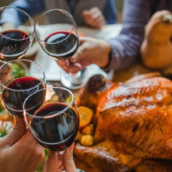 Example of people enjoying red wine with roasted turkey at the dinner table.
