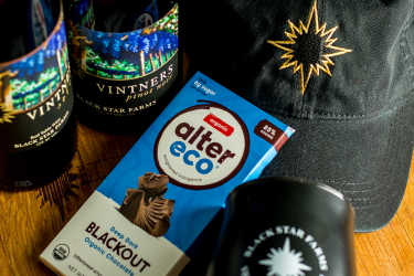 Photo of Black Star Farms Vintners Select, dark chocolate, a logo hat, and wine tumbler.