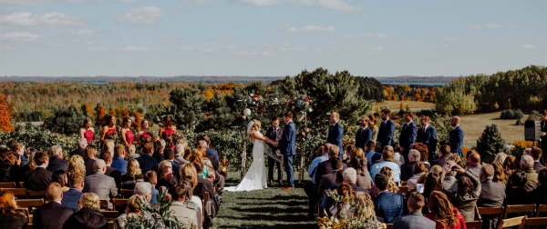 October wedding ceremony with couple and attendees atop our vineyard with beautiful fall colors.