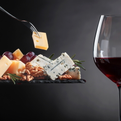 Glass of red wine with a cheese board. including a variety of cheeses and nuts.
