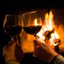 Couple enjoying wine in front of a fireplace at the Inn at Black Star Farms.