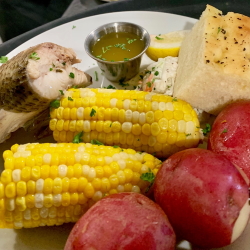 Great Lakes Fish Boil plate with whitefish, corn on the cob , potatoes, coleslaw, and bread.
