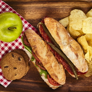 Example of a picnic lunch with sandwiches, chips, an apple and cookies.