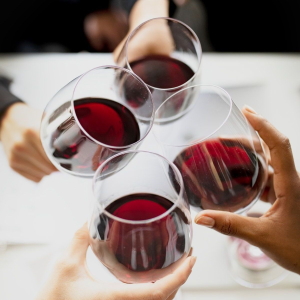 Four people toasting with red wine.