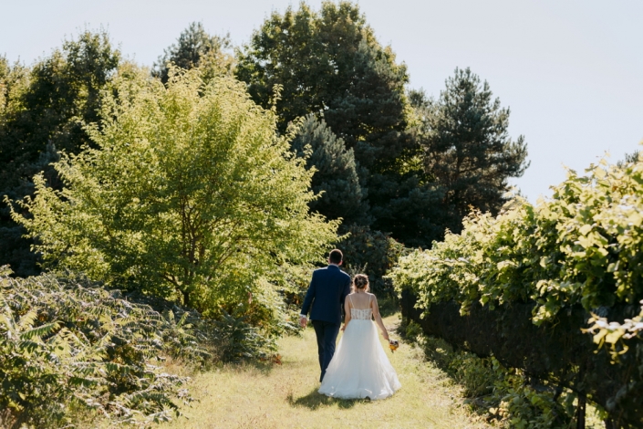 Bride and groom walking through the vineyard.