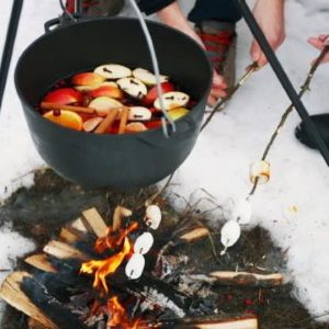 Mulled wine in a pot heating over a bonfire.