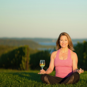 Yoga instructor in the vineyard with wine.