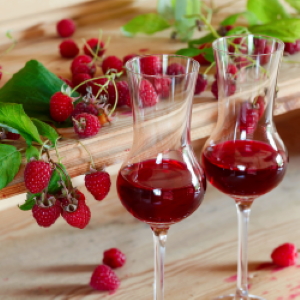 Two glasses of Raspberry Dessert Wine with fresh berries in the background.