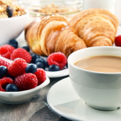 Cup of coffee with fresh fruit and croissants.