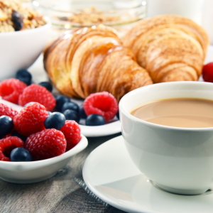 Cup of coffee with fresh fruit and croissants.