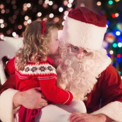 Little girl whispering in Santa's ear.