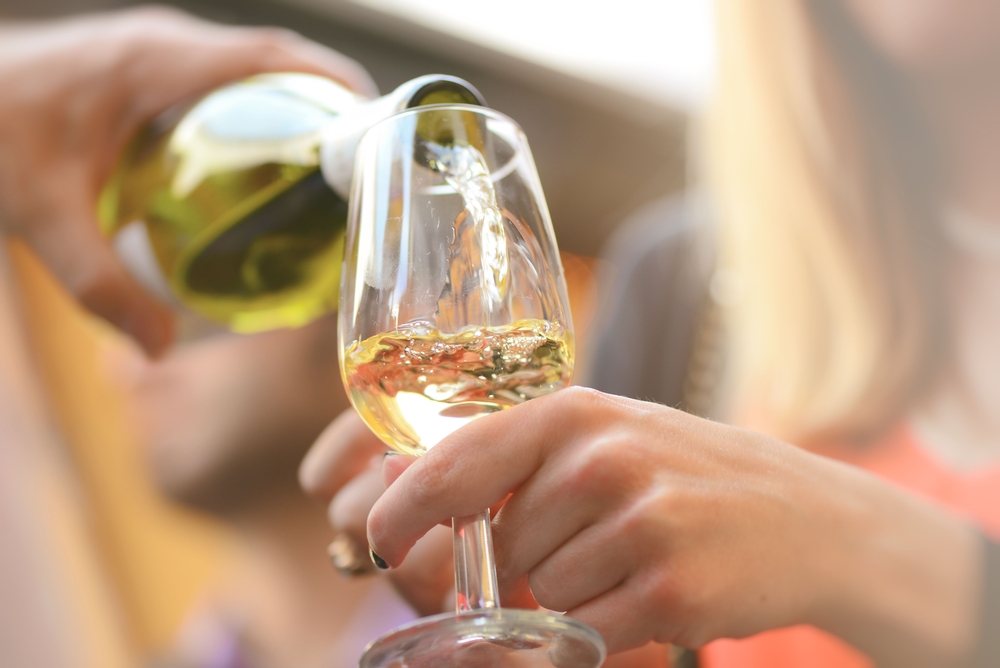 A woman drinking white wine and enjoy the best wine tasting in Traverse City