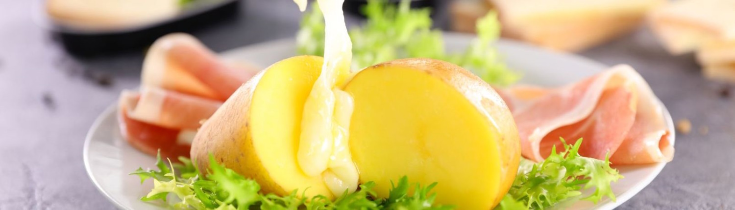 Pouring melted Raclette over potatoes.