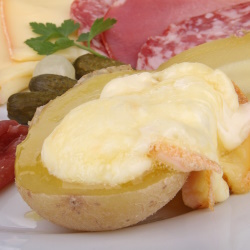 Raclette melted on potatoes with cured meat and cornichons.