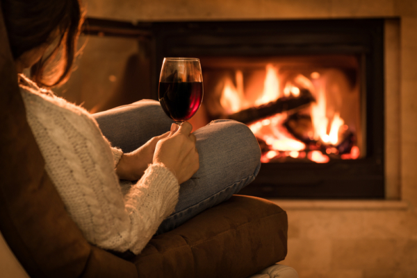 woman sitting in front of the fire with red wine at our Traverse City Bed and Breakfast - the best place to stay for enjoying all the things to do in Traverse City in winter.