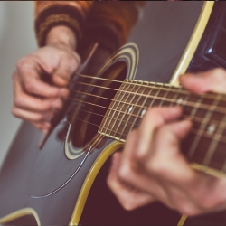 A close up of a person playing the guitar.