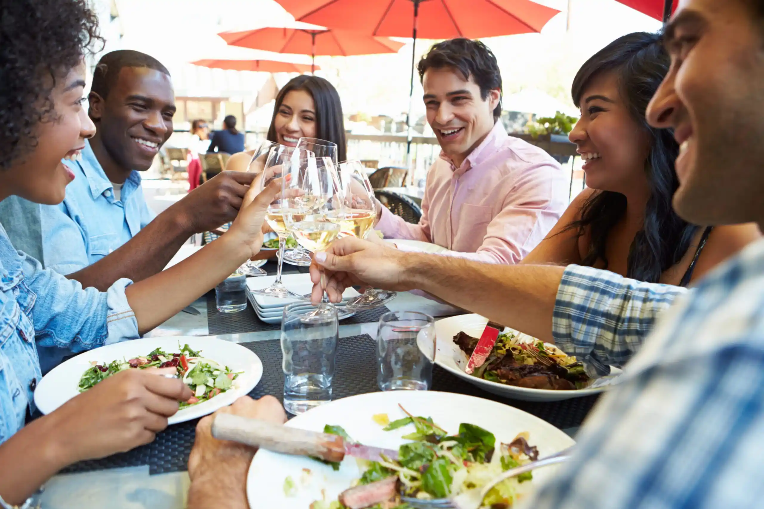 People dining and clinking glasses of white wine.