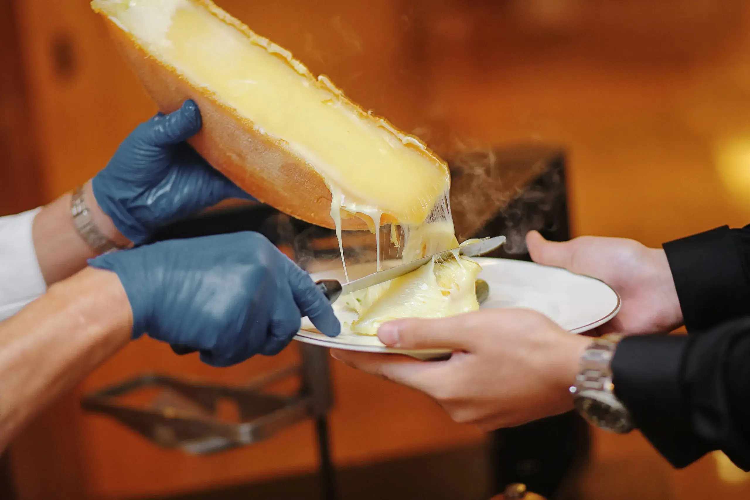 Scraping melted raclette onto a plate of food