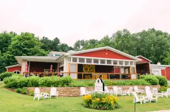 Beautiful red barn adorned with white chairs and flowers.