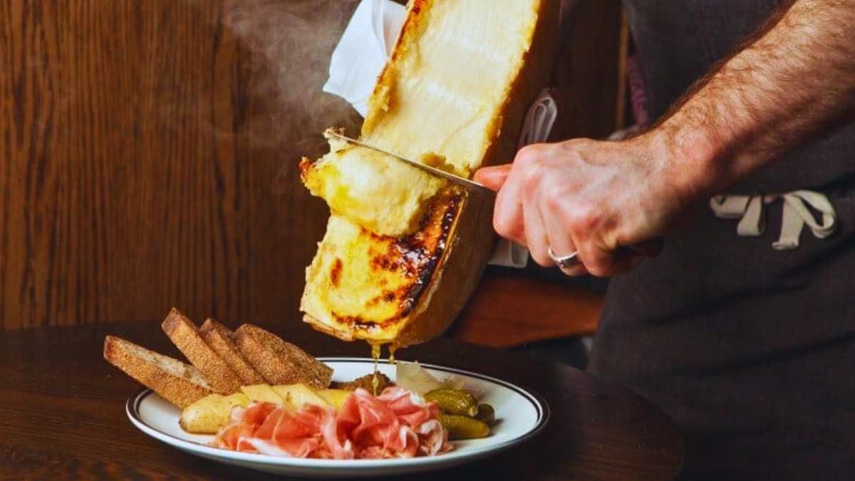 Scraping melted Raclette over meat and potatoes