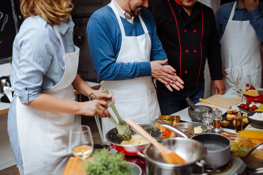 People in a cooking class while enjoying wine.