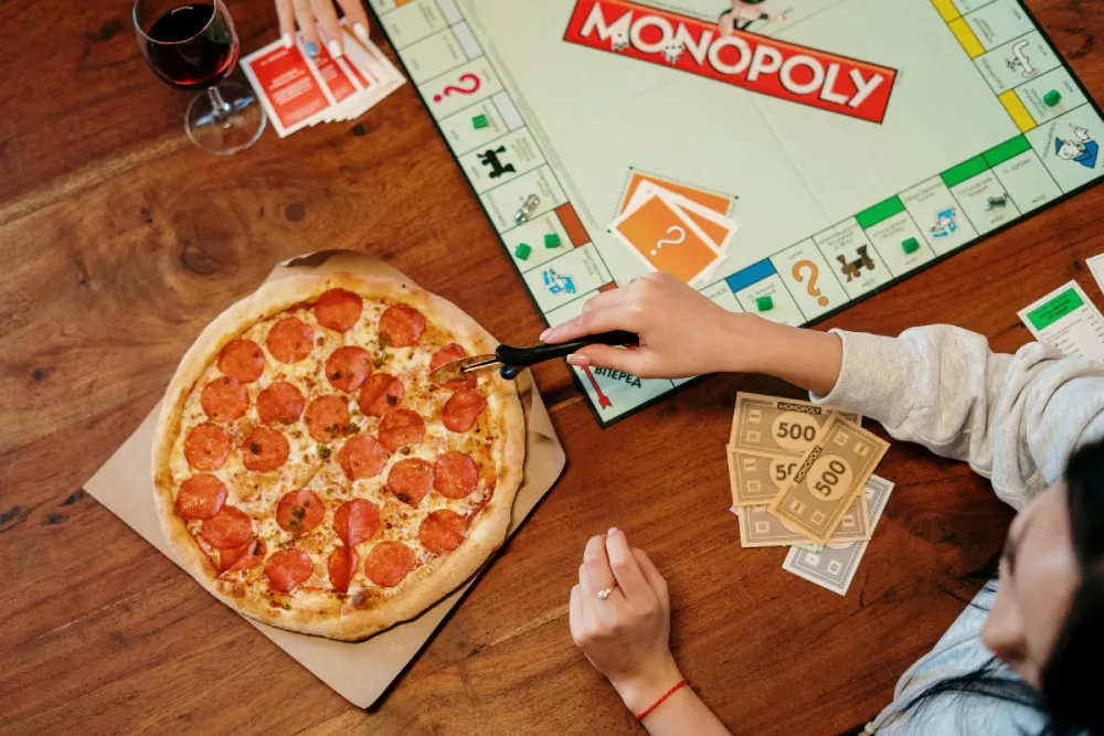 People playing Monopoly with pizza and wine