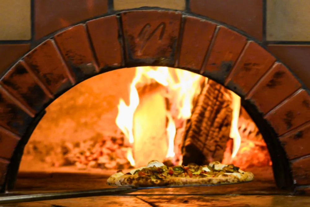 Removing a pizza from our wood fired oven at Bistro Polaris