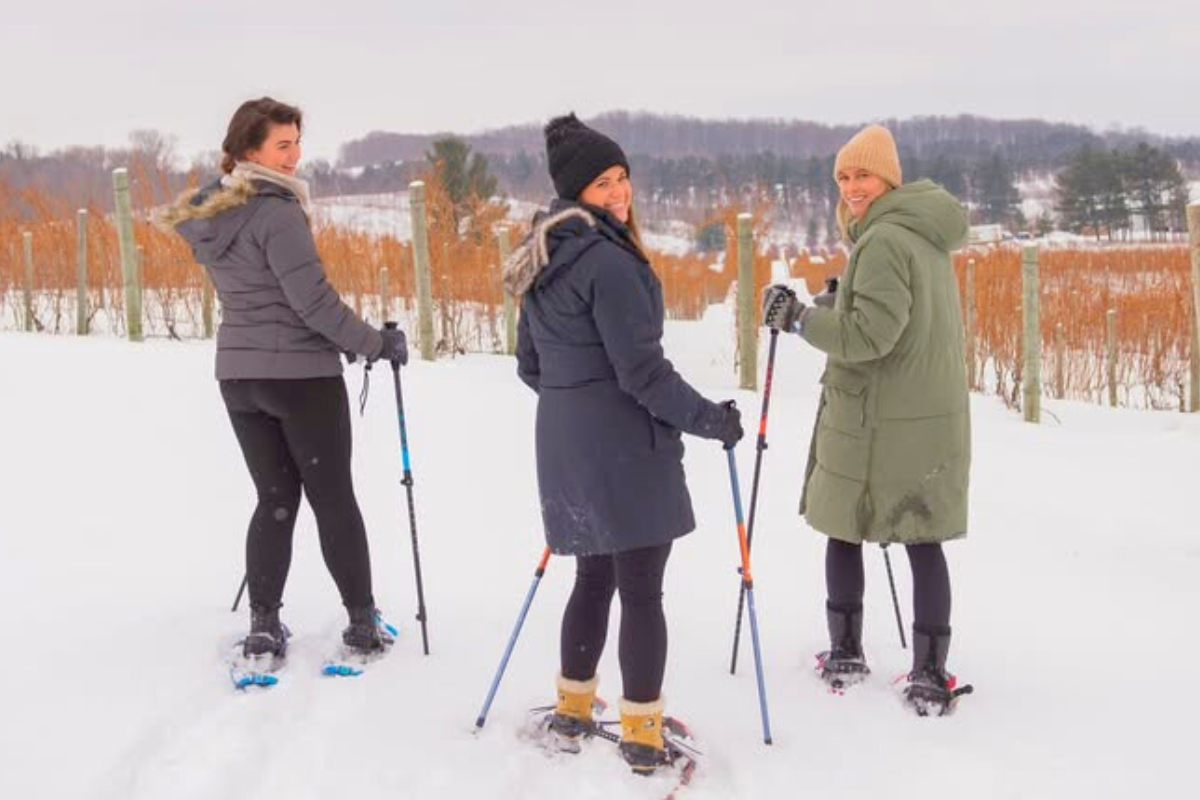 Three ladies snowshoeing in a vineyard.