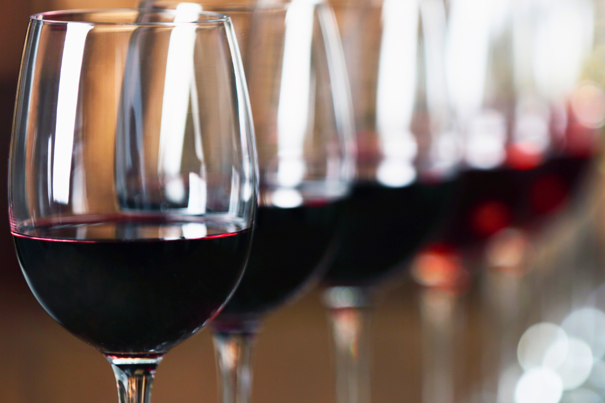 A series of wine glasses with red wine.