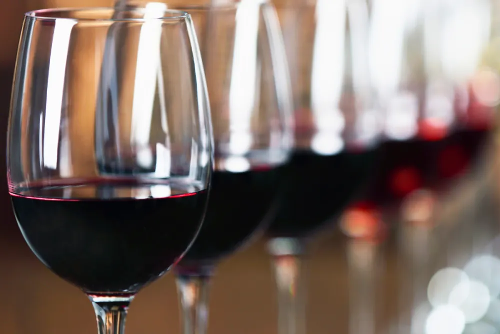 A series of wine glasses with red wine.