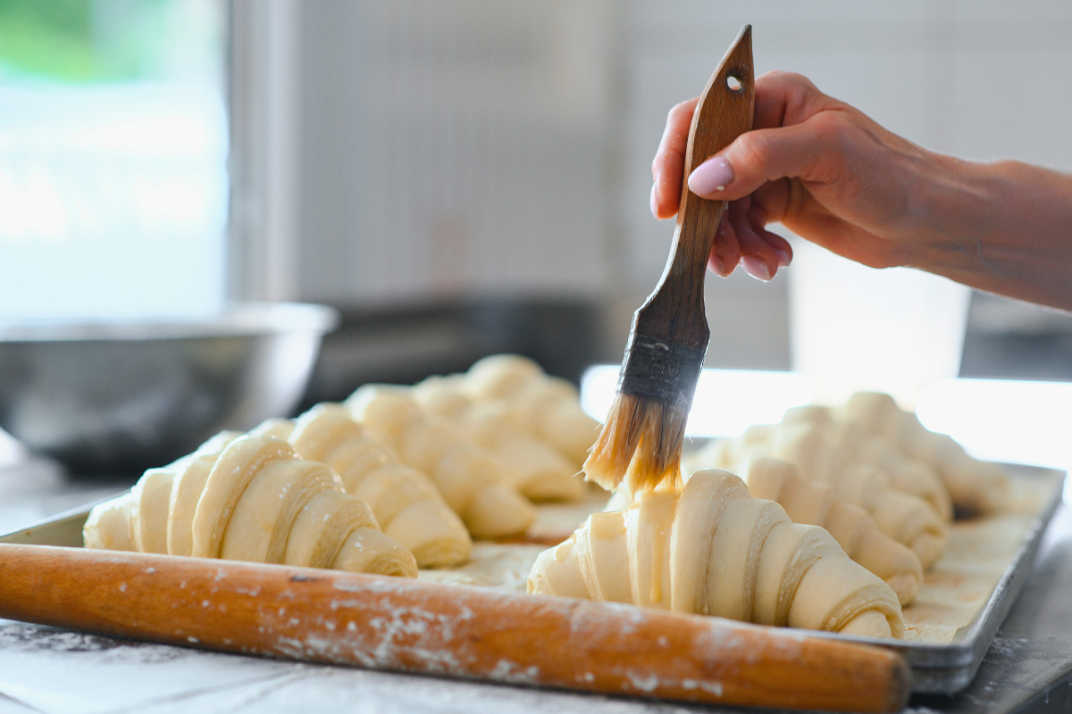 Person brushing the top of prepared croissant dough